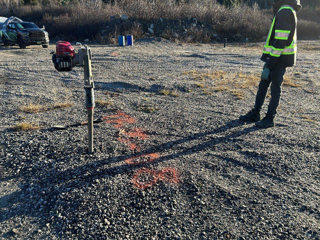 Motorized hand auger set in gravelly soil, next to a technician