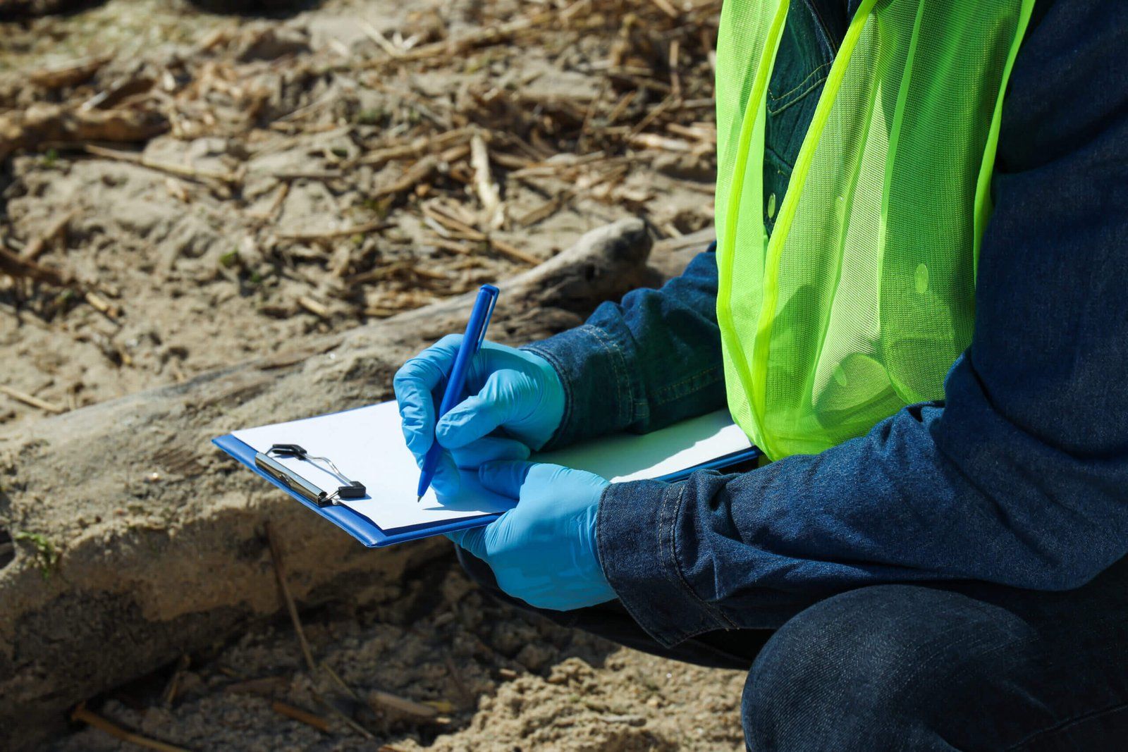 Technicien qui consigne un prélèvement sur une fiche de terrain, sur un site à caractériser